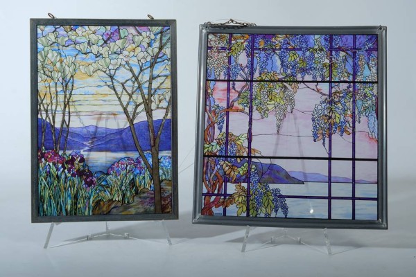 ZWEI JUGENDSTIL GLASBILDER Weinreben und Landschaft 28x30,5cm, Bäume und Hügellandschaft 21.5x31cm, beide Glasgemälde sind eingerahmt, Weinreben mit einer Seelandschaft und Inseln im Hintergrund: 31x33cm und Bäume mit einer Hügellandschaft und einem See im Hintergrund, sowie Blumen im Vordergrund: 23x33cm, weiter ist an beiden Gemälde je eine Kette befestigt zur Hängung