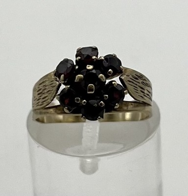Granatring, 333 Gelbgold, Größe 51. Breiter Goldring, der im Blattdekor zur Granat-Blume führt. 2,1g.