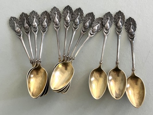Mokkalöffel, 800 Silber (punziert), zwölf Stück. Die Griffe ausgearbeitet als Pfau, vergoldete Laffe. Gesamt 135g.