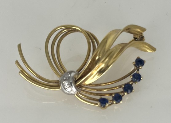 Brosche, 585 Gelbgold mit vier Saphiren und drei Brillanten. Filigran gearbeitet mit einzelnen dünnen Strängen, die sich in eine Schleifenform winden. Am Knoten durch Brillanten geziert.