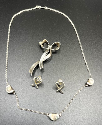 Tiffany und Co. Konvolut aus Kette, Ohrringe, Brosche, 925 Sterlingsilber. Eine Brosche in Schleifenform, 1985. Zwei Ohrstecker in Herzform und eine Silberkette mit drei Herzen.