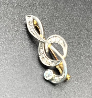 Brosche, 750 Gelbgold, mit Brillanten um 0,19ct, Notenschlüssel. Feine Brosche in Form eines Notenschlüssels. Diese bestückt mit verschiedenen Brillanten. Der größte Brillant um 0,1ct.
