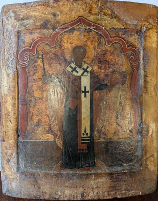 Bischof, vermutlich Heiliger Nikolaus von Myra, ca. 17./18. Jahrhundert, russische Ikone. Die Ikone zeigt eine stehende religiöse Figur, vermutlich den Heiligen Nikolaus von Myra, in traditioneller kirchlicher Gewandung. Sie ist mit Eitempera auf Holz gemalt und weist deutliche Alters- und Gebrauchsspuren auf - Risse, Abplatzungen und dunkle Verfärbungen deuten auf ein hohes Alter hin.
