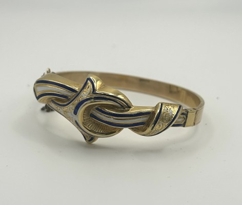 Armspange mit Emaille-Elementen in Blau und Weiß, 585 Gelbgold, Biedermeier. Schön gestaltete Armspange mit kunstvoll eingearbeiteten Emaille-Elementen. Die plastische, schwungvolle Formgebung wird durch die feine Emaille Arbeit hervorgehoben und verleiht besondere Tiefe. Das kunstvolle Knotenmuster ist ein beliebtes Motiv der Epoche. Steckverschluss mit Sicherheitskette.