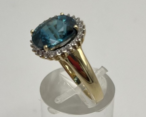 Goldring, mit blauem Zirkon, umgeben von kleinen Brillanten 585 Gelbgold, Größe 57. Schön gearbeiteter Ring mit mittig gefasstem Zirkon.