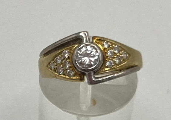 Brillantring, 750 Bicolor Gold, Brillant um 0,5ct, mit weiteren zwölf Brillanten je um 0,02ct, Größe 55. Mittig gefasster Brillant, der durch geometrische Weißgold Elemente von dem Gelbgold des Rings hervorgehoben wird. Flankiert von weiteren Brillanten.